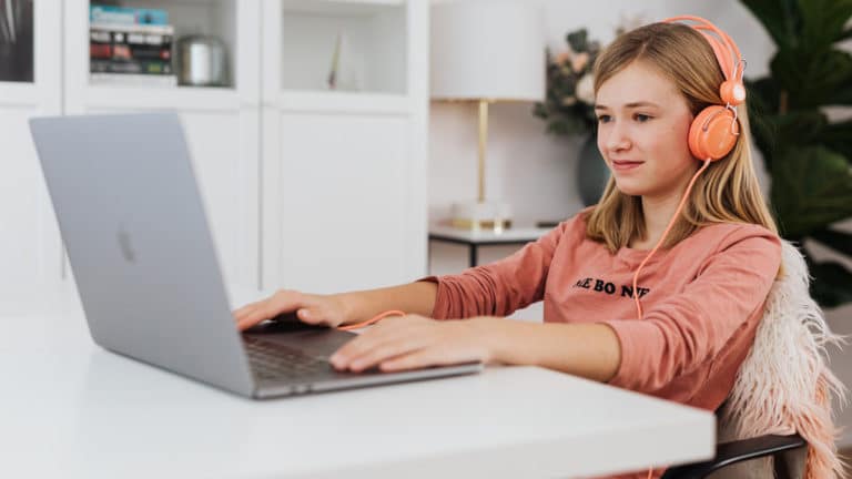 girl wearing headphones learning online with laptop