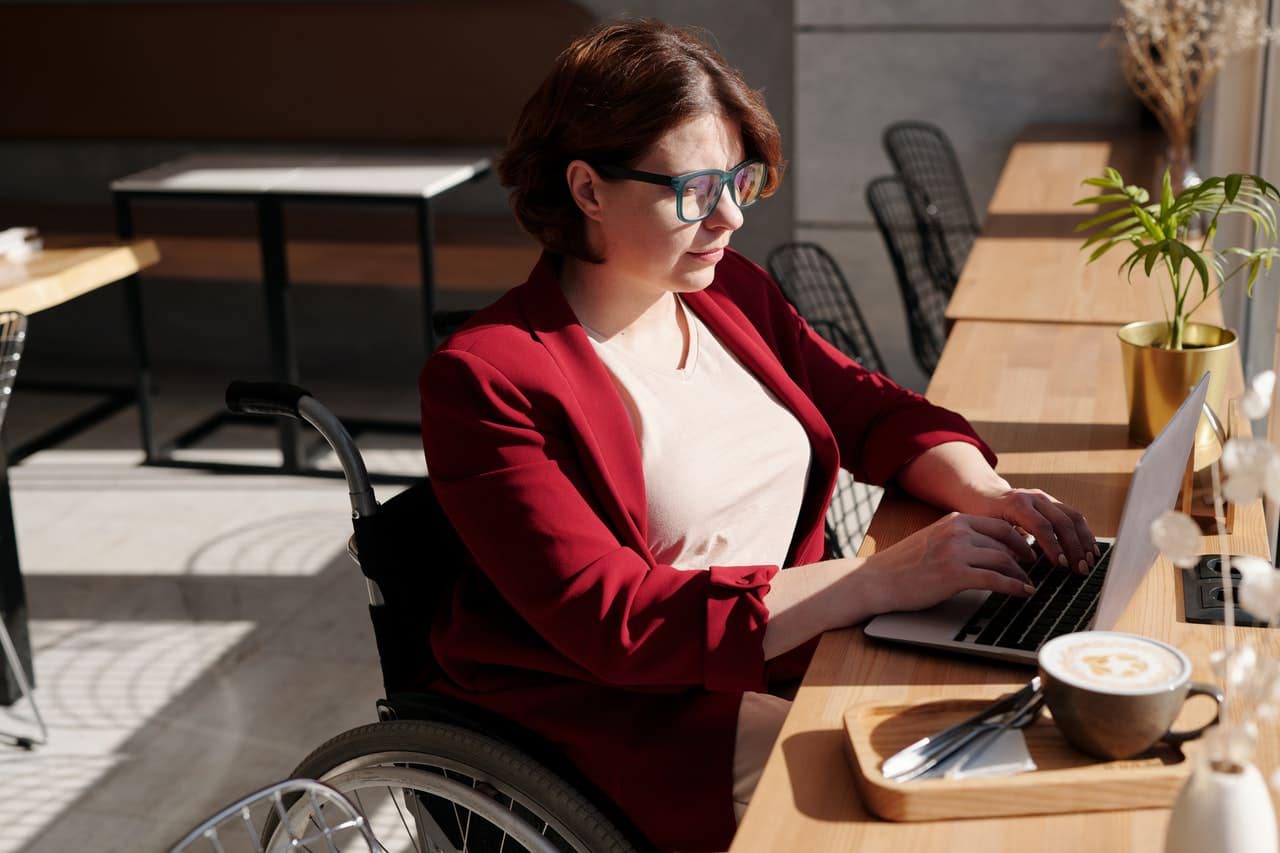 woman on wheelchair in cafe working online
