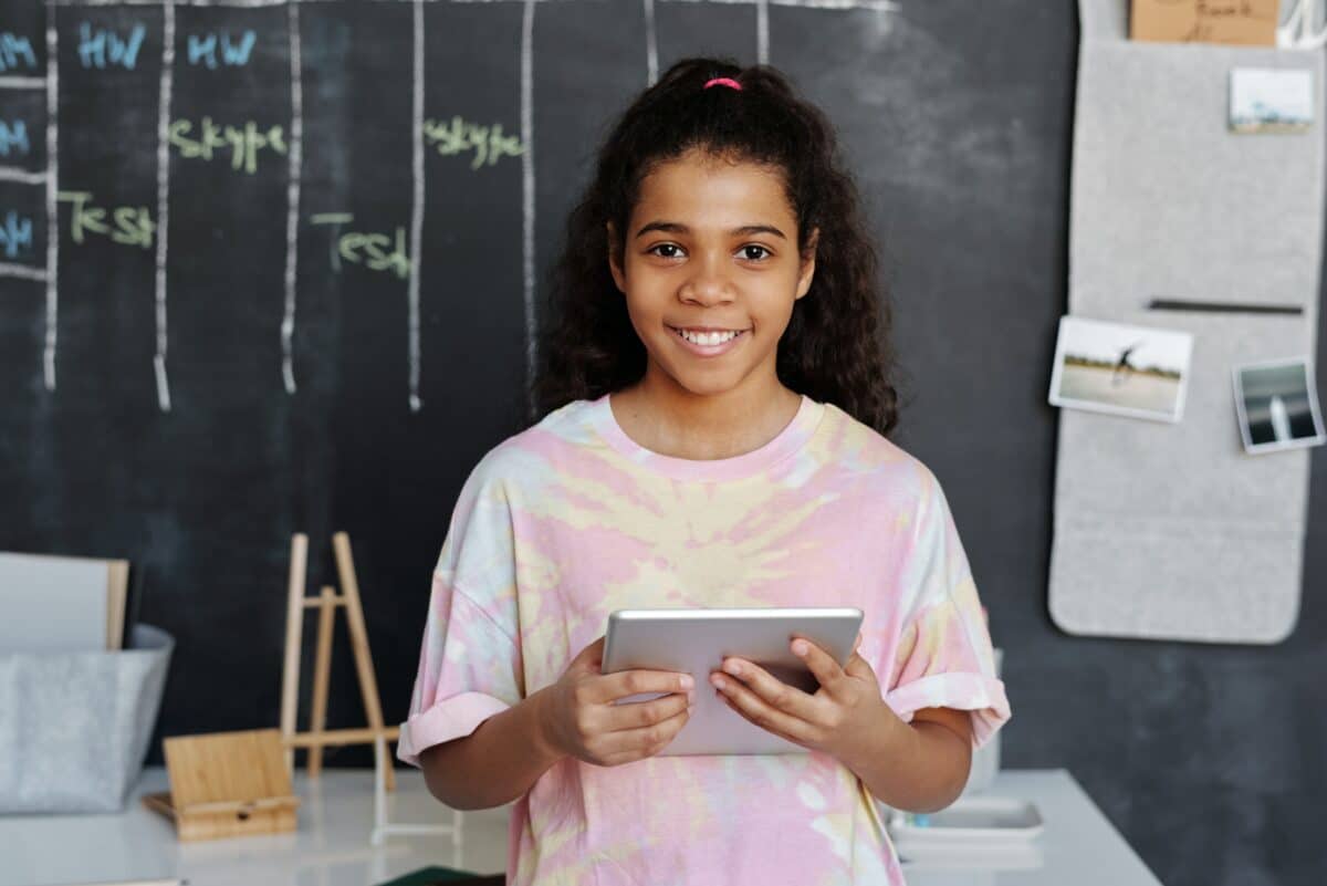 A student smiling while holding tablet