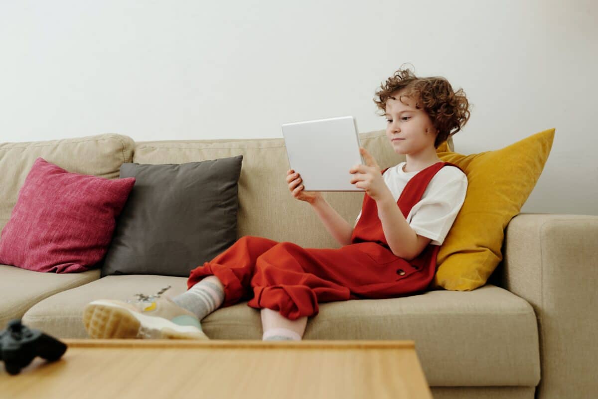 A kid learning from tablet on a couch